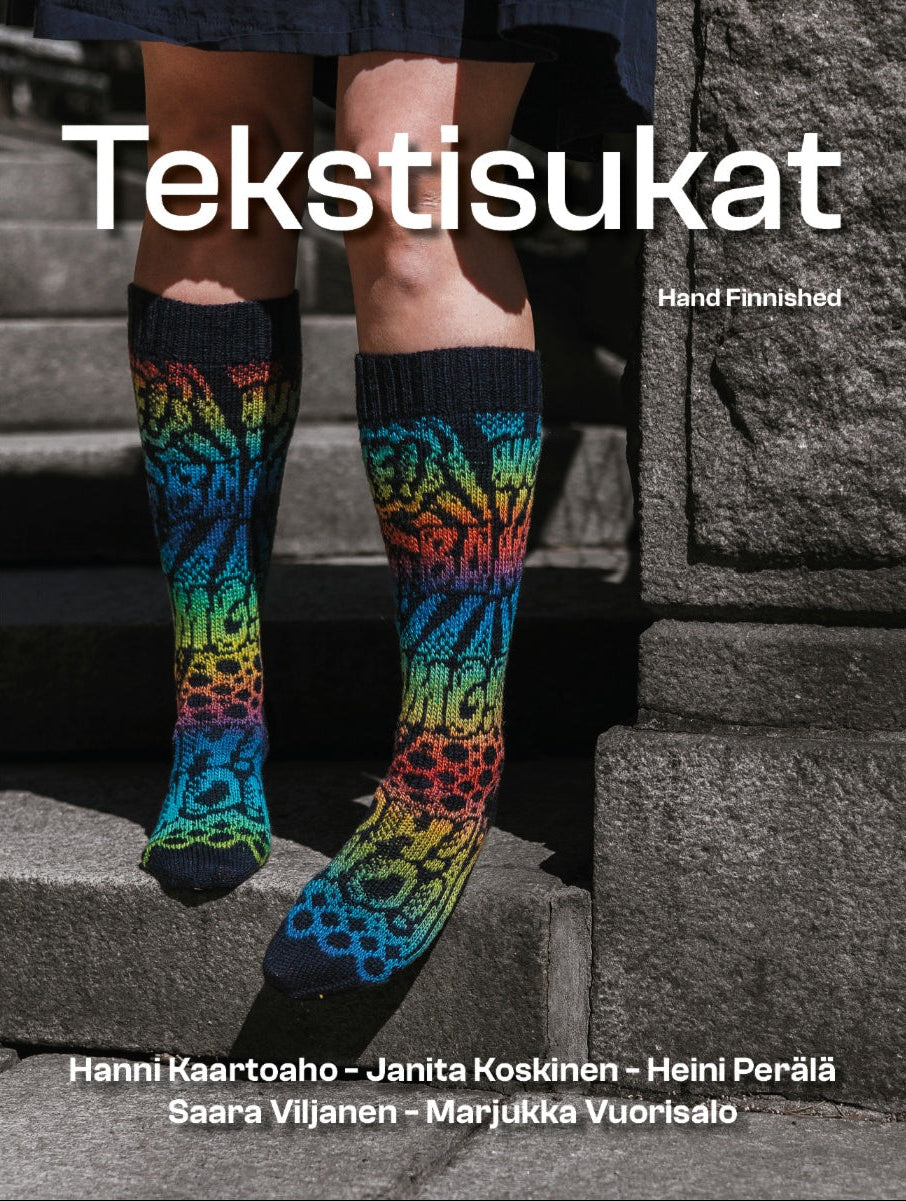 The cover of Tekstisukat showing a person from the knees down wearing colorful knit socks with a rainbow gradient and onomatopeia words, standing on stone steps. Large white text reads 'Tekstisukat' with smaller text 'Hand Finnished' and author names at the bottom.