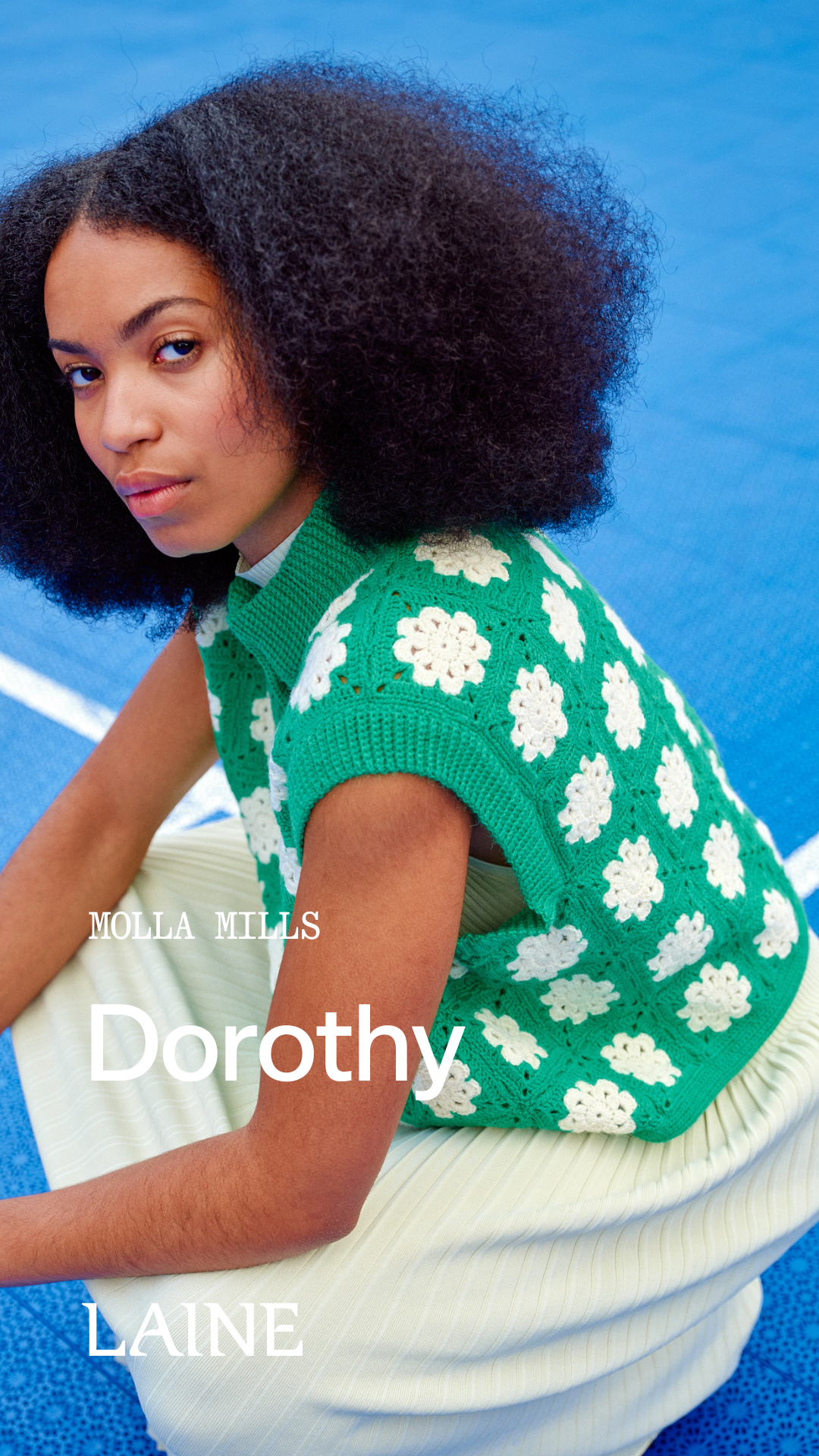 Woman wearing a green floral sleeveless Dorothy top designed by Molla Mills against a blue background