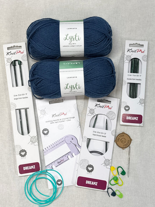 Knitting supplies including yarn, needles, and tools on a gray surface